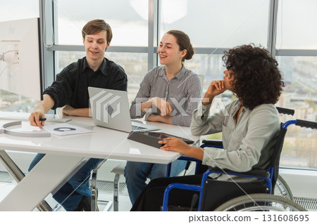 Teamwork brainstorm. Diverse multiracial colleagues woman in chair for people with disability working together. Group of people sitting in creative office discussing business. Young professional team 131608695
