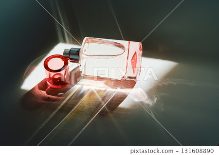 Pink perfume bottle on the light background in the rays of sun with highlights. 131608890