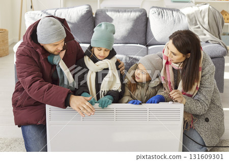 Family freezing near heater at home, suffering in cool flat, shivering tremble with cold, unhappy 131609301