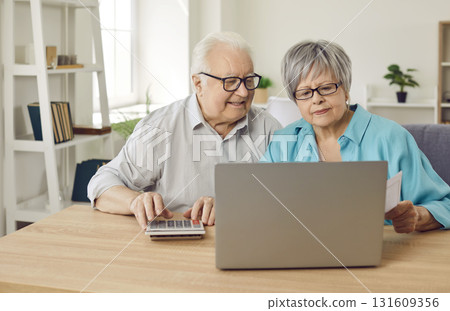 Elderly senior couple sitting at the table with laptop calculating finances planning family budget Elderly senior couple sitting at the table with laptop calculating finances planning family budget 131609356