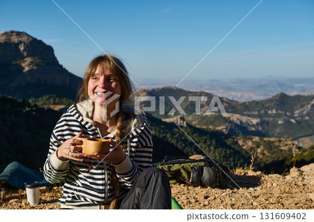 Smiling Hiker Woman Enjoying Coffee On Mountain Trail With Scenic Valley View 131609402