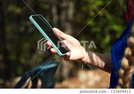 Outdoor Smartphone Use On Trail: Teal Case Hand Holds Phone While Hiking 131609411