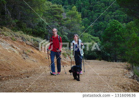 Hiking Couple With Dog On Rustic Trail Through Green Forest Hiking Couple With Dog On Rustic Trail Through Green Forest 131609636