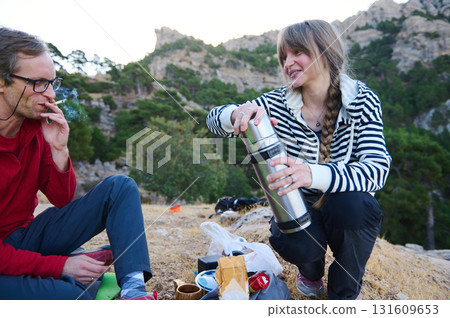 Outdoor Friends Take a Break: Hikers Enjoy Thermos Coffee Break Amid Rocky Hills and Trees Outdoor Friends Take a Break: Hikers Enjoy Thermos Coffee Break Amid Rocky Hills and Trees 131609653