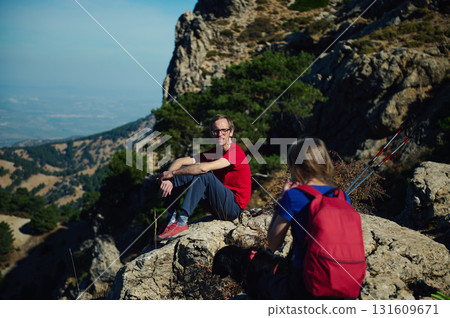 Hikers Rest On Mountain Ridge With Backpack And Trekking Poles Hikers Rest On Mountain Ridge With Backpack And Trekking Poles 131609671