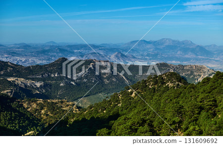 Scenic Mountain Range Over Rolling Forested Hills Under Clear Blue Sky Scenic Mountain Range Over Rolling Forested Hills Under Clear Blue Sky 131609692
