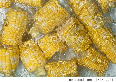 Aesthetic summer bright background of fresh ripe corn cob in water. 131609721