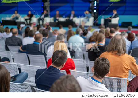 Panel discussion at a large conference with audience seated and experts on stage 131609790