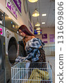 Young Man Taking Clothes Out of the Washing Machine in Self-Service 131609806