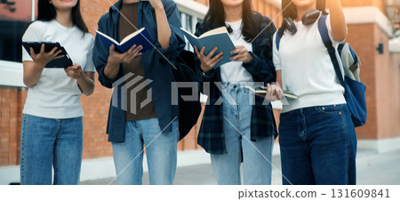 Happy students walking together on university campus, chatting and laughing outdoors after classes 131609841