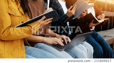 Happy students walking together on university campus, chatting and laughing outdoors after classes 131609917