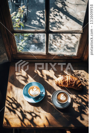 Enjoying the warmth of coffee and a croissant while rain lightly falls outside, creating a cozy ambiance in the caf Enjoying the warmth of coffee and a croissant while rain lightly falls outside, creating a cozy ambiance in the caf 131609958