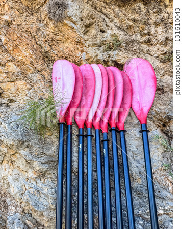 Group of Red Kayak Oars Resting on a Rock Wall Group of Red Kayak Oars Resting on a Rock Wall 131610043