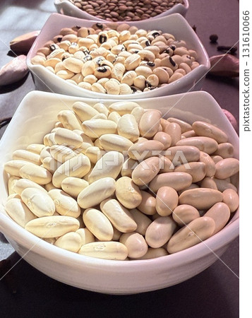 White beans, lentils, and black-eyed peas in white bowls on a black surface. Healthy, wholesome, plant-based food. White beans, lentils, and black-eyed peas in white bowls on a black surface. Healthy, wholesome, plant-based food. 131610066