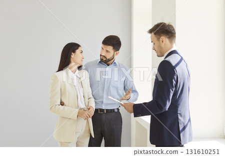 Young couple standing with realtor, discussing options and making decision about purchase or rent. 131610251