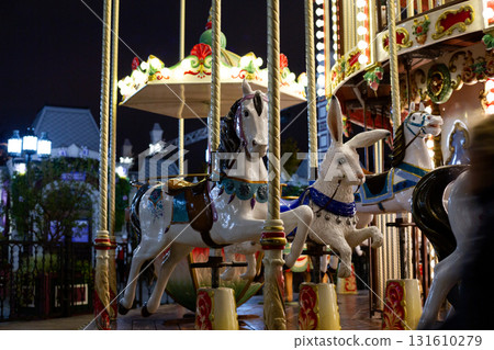 Illuminated carousel ride with colorful horses and rabbit figure, evoking sense of nostalgia and fun. Perfect for children entertainment, and festive events. Creating joyful memories Illuminated carousel ride with colorful horses and rabbit figure, evoking sense of nostalgia and fun. Perfect for children entertainment, and festive events. Creating joyful memories 131610279