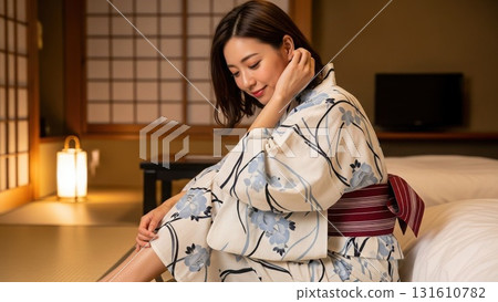 A woman in a yukata sitting on a futon, looking back and smiling shyly A woman in a yukata sitting on a futon, looking back and smiling shyly 131610782