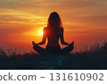 Silhouette of a woman practicing yoga at sunset 131610902