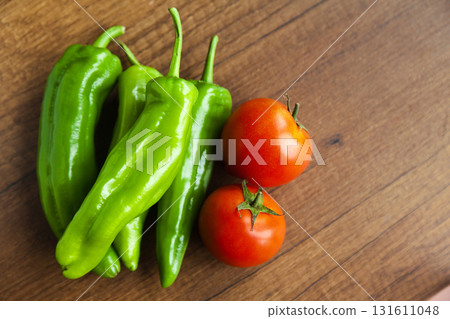 Fresh, tasty organic vegetables, red tomato and green pepper, isolated on brown wood cutting board 131611048