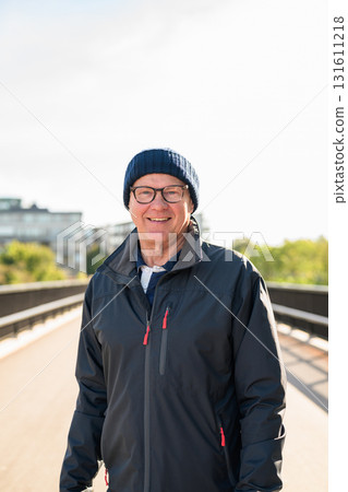 Portrait of a smiling senior man in sportswear on the bridge in Europe 131611218