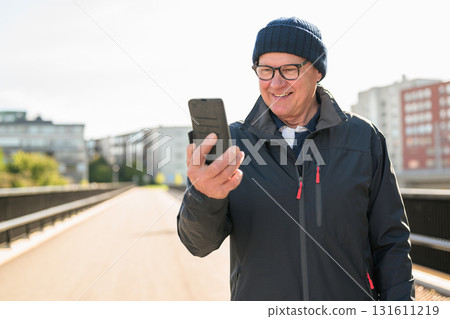 Portrait of senior man using mobile phone while standing on the bridge 131611219