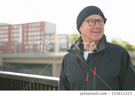Portrait of a smiling senior man in sportswear on the bridge in Europe 131611223