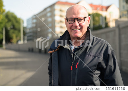 Portrait of a smiling bald senior man with glasses wearing a sport jacket outdoors Portrait of a smiling bald senior man with glasses wearing a sport jacket outdoors 131611238