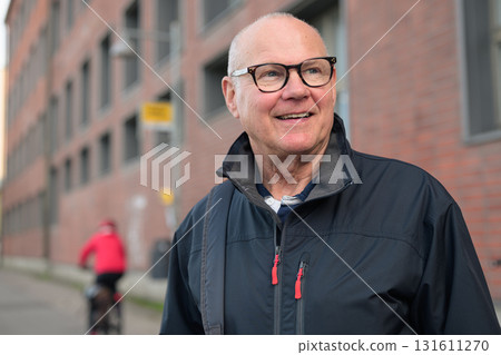 Portrait of a smiling senior man with eyeglasses waiting at a bus stop in the city 131611270