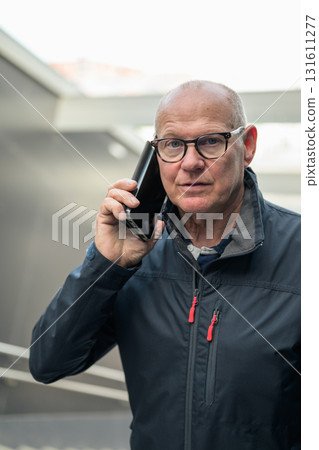 Portrait of senior man using mobile phone while standing in subway station Portrait of senior man using mobile phone while standing in subway station 131611277