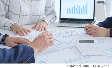 Business people analyzing financial data and market trends during a corporate meeting, collaborating on reports and planning strategic growth in modern office 131612466