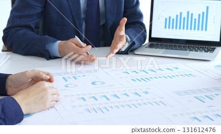 Business people reviewing financial charts and reports in office, using a laptop and calculator while engaging in discussions about strategy and performance Business people reviewing financial charts and reports in office, using a laptop and calculator while engaging in discussions about strategy and performance 131612476