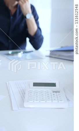 Businessman is having problems with finance, he's stressed and thinking about solutions, focusing on calculator and documents. Audit and taxes in business 131612548
