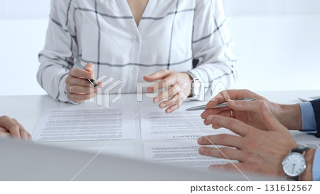 Business professionals or lawyers sitting at the desk in a bright office, reviewing and discussing contract papers. Teamwork concept Business professionals or lawyers sitting at the desk in a bright office, reviewing and discussing contract papers. Teamwork concept 131612567