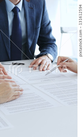 Business colleagues reviewing contract documents during an office meeting, discussing terms, and preparing for agreement signing, focusing on legal consultation and partnership discussion Business colleagues reviewing contract documents during an office meeting, discussing terms, and preparing for agreement signing, focusing on legal consultation and partnership discussion 131612594