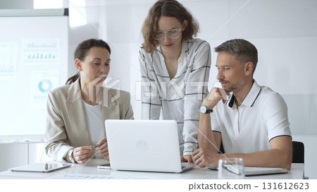 Business people team collaborating and analyzing data on a laptop during a productive meeting in a modern office, fostering teamwork and strategic decision making Business people team collaborating and analyzing data on a laptop during a productive meeting in a modern office, fostering teamwork and strategic decision making 131612623
