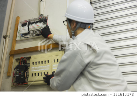 A man in work clothes doing electrical work A man in work clothes doing electrical work 131613178