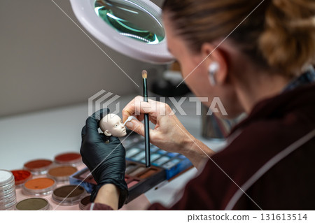 Artist painting silicone doll face with fine brush Artist painting silicone doll face with fine brush 131613514