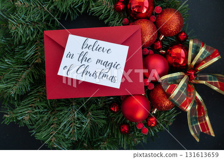 Greeting card with BELIEVE IN THE MAGIC OF CHRISTMAS text on handmade Christmas wreath. Festive mood new year celebration. Postcard decoration decor Greeting card with BELIEVE IN THE MAGIC OF CHRISTMAS text on handmade Christmas wreath. Festive mood new year celebration. Postcard decoration decor 131613659