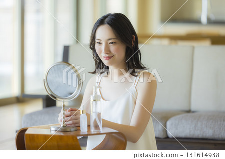 A woman looking in the mirror in the living room 131614938