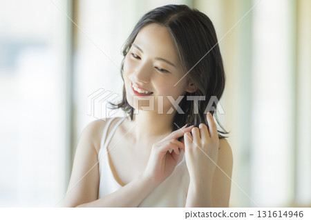 A woman doing hair care in the living room 131614946