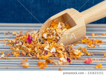 Wooden Scoop Overflowing with Colorful Dried Flowers on Striped Tablecloth Surface 131615151