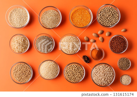 Diverse Array of Colorful Spices and Grains in Glass Bowls on Vibrant Orange Background 131615174