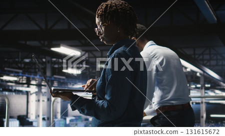 Data center engineer walking on industrial platform, running diagnostics on equipment to identify errors. Server farm IT professionals preventing rigs failure to minimize downtime, Data center engineer walking on industrial platform, running diagnostics on equipment to identify errors. Server farm IT professionals preventing rigs failure to minimize downtime, 131615672