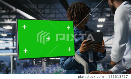 Data center colleagues working on green screen PC, updating storage infrastructure. IT engineering team using mockup computer in server hub workspace filled with networking tech 131615717