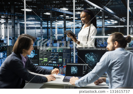 Teamworking data center admins adjusting neural networks model parameters to upgrade systems. Server room IT colleagues scheduling machine learning ran maintenance for infrastructure components Teamworking data center admins adjusting neural networks model parameters to upgrade systems. Server room IT colleagues scheduling machine learning ran maintenance for infrastructure components 131615737