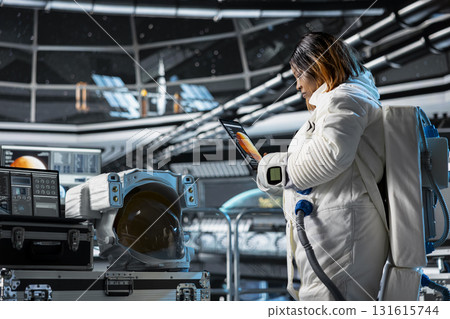 Cosmonaut studies mission plans on tablet before Mars expedition, preparing for future of mankind. Woman in starship explores red planet in search of signs that could support human life beyond Earth 131615744