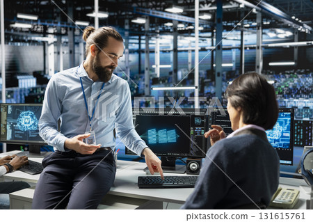 Teamworking data center colleagues managing AI training datasets using PC. Team of engineers doing brainstorming, overseeing machine learning in server room supporting scalable equipment for AI apps 131615761