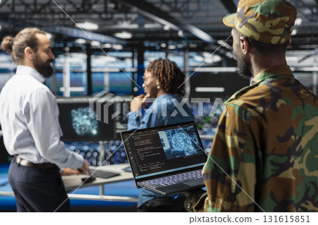 Military technicians in data center reviewing drone surveillance footage on laptop screen. Army unit officer in high tech server farm doing battlefield reconnaissance operations via drone control. Military technicians in data center reviewing drone surveillance footage on laptop screen. Army unit officer in high tech server farm doing battlefield reconnaissance operations via drone control. 131615851