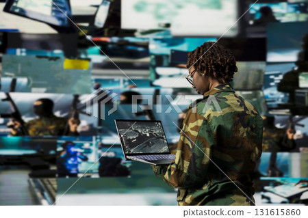 Soldier using warning system software on laptop in control room to monitor incoming enemy aerial attacks. African american army agent maintains air space superiority with radar during armed conflict Soldier using warning system software on laptop in control room to monitor incoming enemy aerial attacks. African american army agent maintains air space superiority with radar during armed conflict 131615860