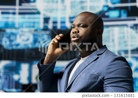 Black tech specialist talking on a smartphone call in an AI powered environment, representing predictive algorithms and machine learning systems. Working on automation and innovation. 131615881